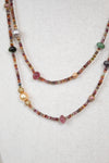 Close-up of layered necklace with autumnal colored multi-sized beads against a plain background