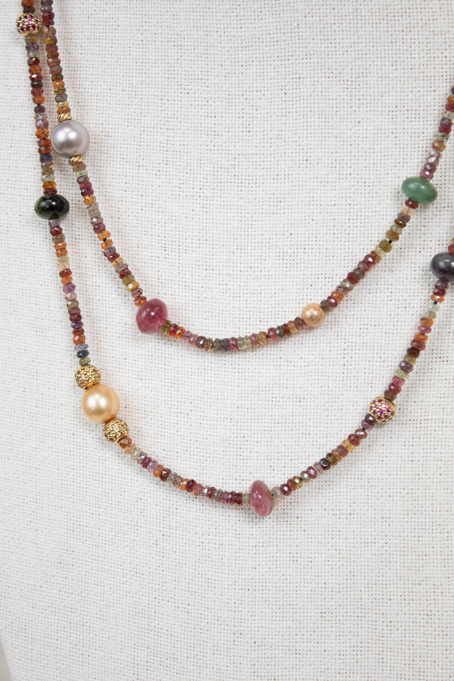 Close-up of layered necklace with autumnal colored multi-sized beads against a plain background