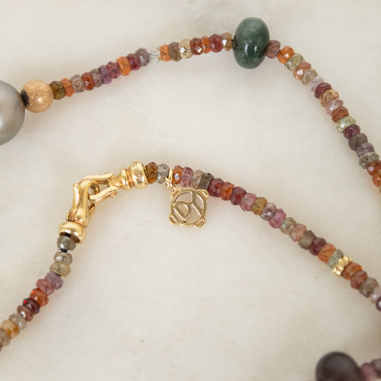 Close up of autumnal colored beads showing 'David Yurman' logo on gold closure