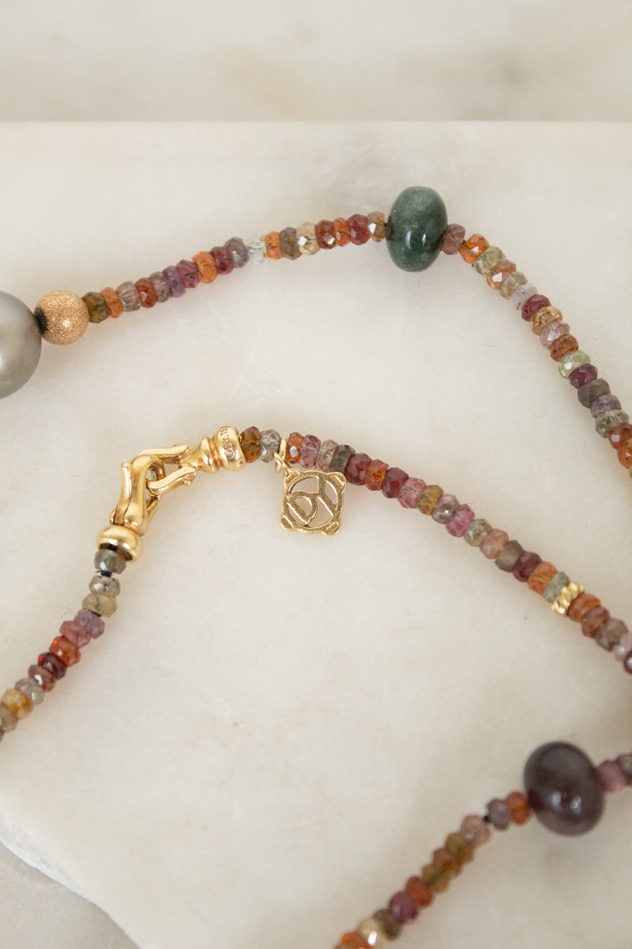 Close up of autumnal colored beads showing 'David Yurman' logo on gold closure