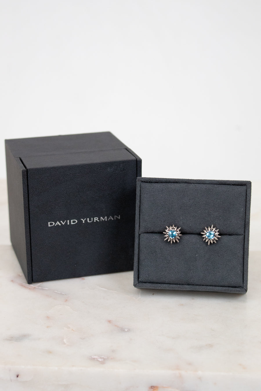 Silver starburst shaped earrings with blue stone in center. 