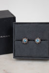 Pair of starburst earrings with blue gemstones in center on a black jewelry box.