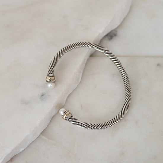 Silver bracelet with pearl detail ends on a marble surface