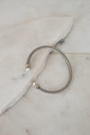 Silver bracelet with pearl detail ends on a marble surface