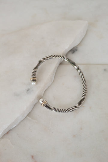 Silver bracelet with pearl detail ends on a marble surface