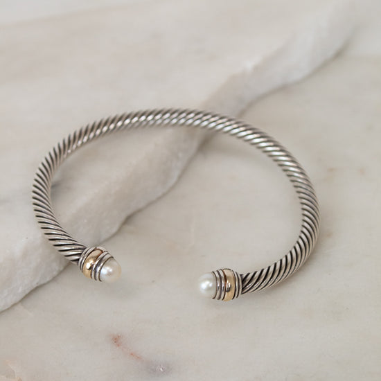 Silver bracelet with pearl accents on a marble surface