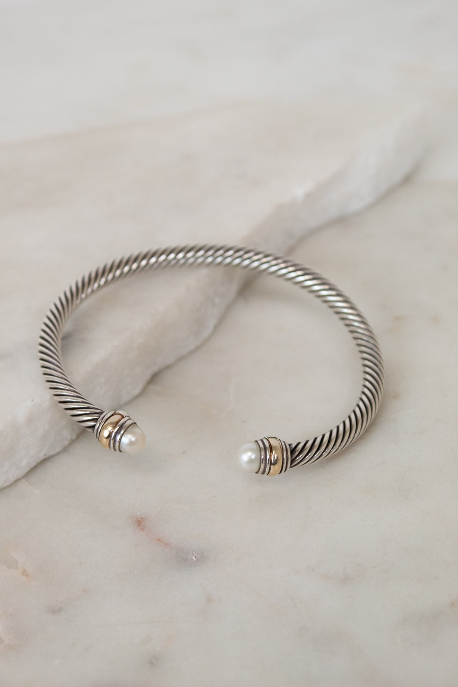 Silver bracelet with pearl accents on a marble surface