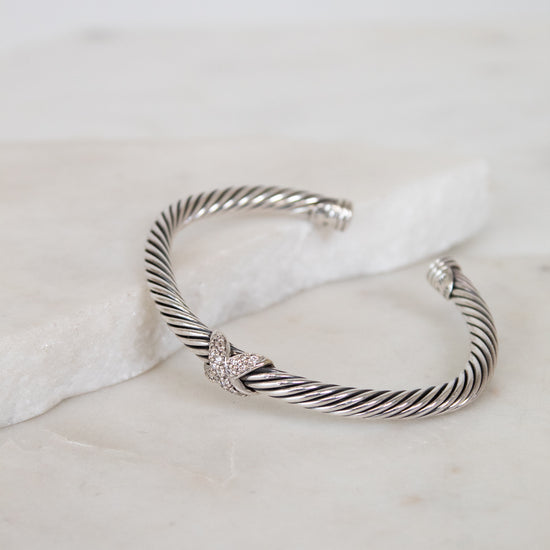 Silver bracelet with a gold and diamond station on a marble surface