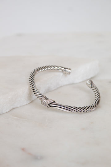 Silver bracelet with a gold and diamond station on a marble surface