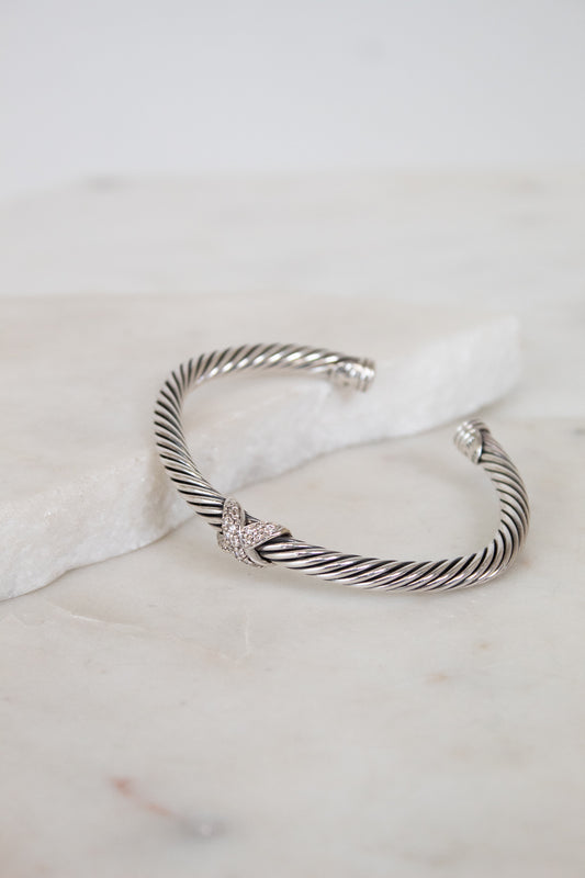 Silver bracelet with a gold and diamond station on a marble surface