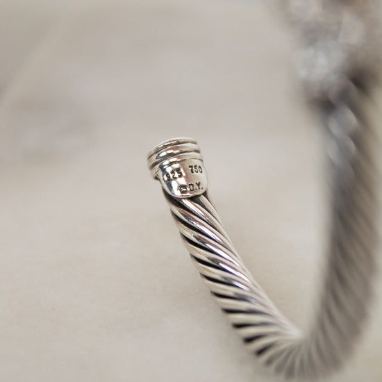 Close-up of a silver bracelet with a textured design on a light background