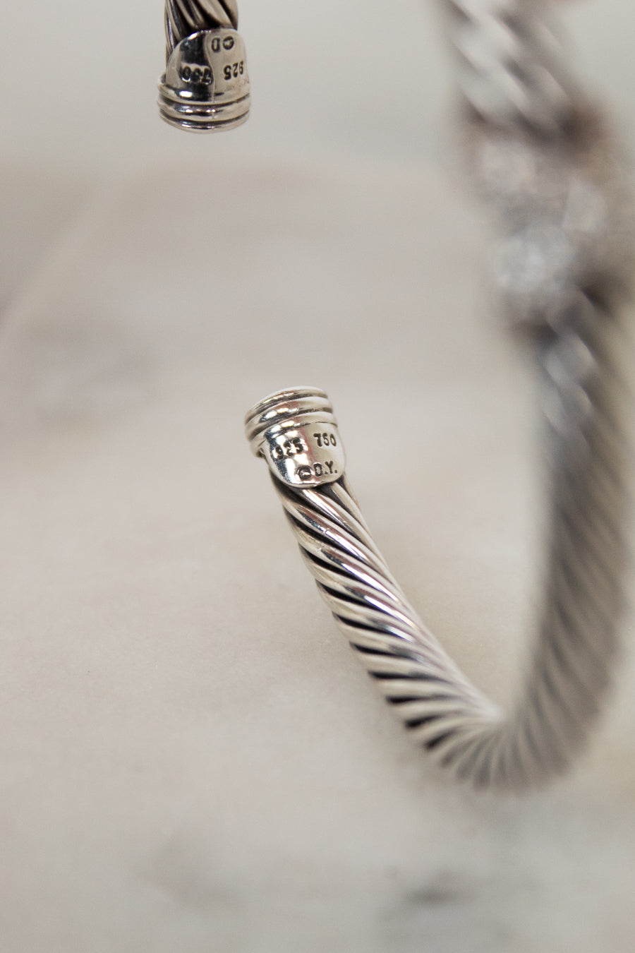 Close-up of a silver bracelet with a textured design on a light background