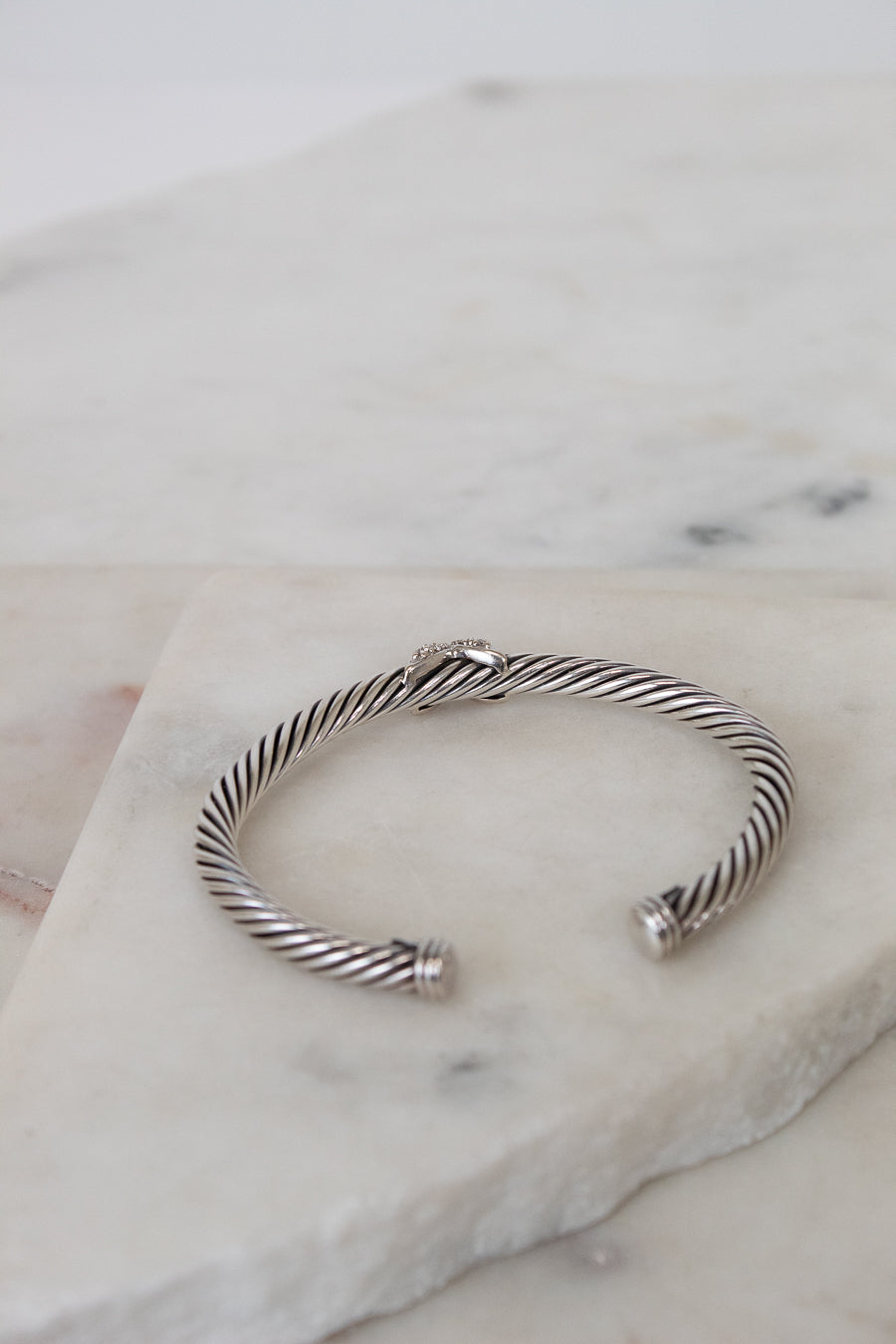 Silver cable cuff bracelet on a marble surface
