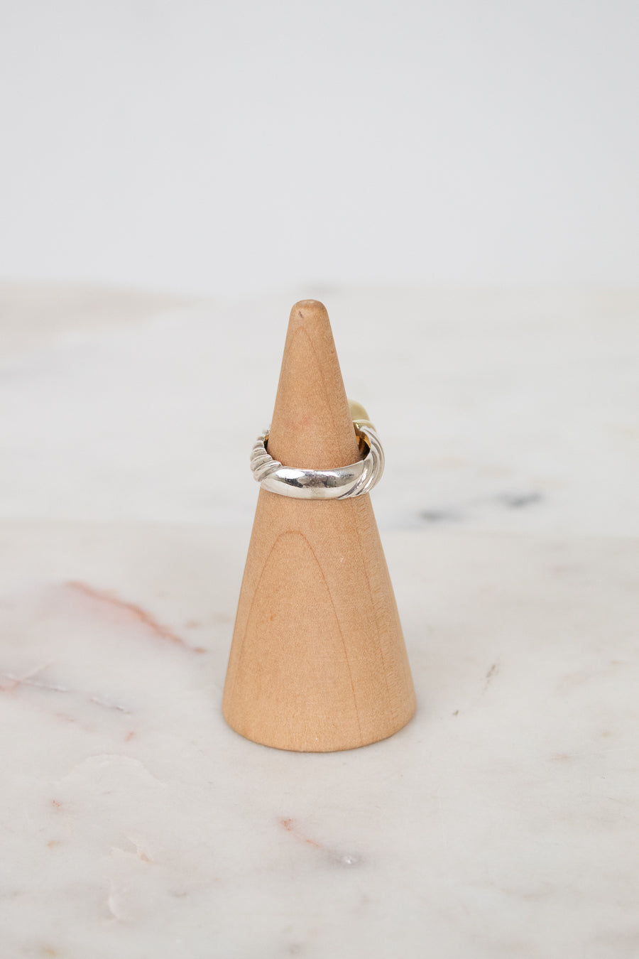 Back view of silver ring on wooden stand