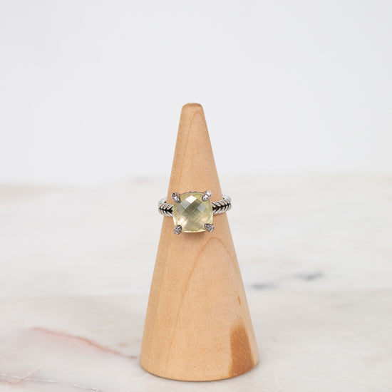 Ring with a yellow gemstone on a wooden cone against a white background