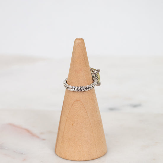 Silver ring on a wooden cone against a white background