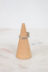 Silver ring on a wooden cone against a white background