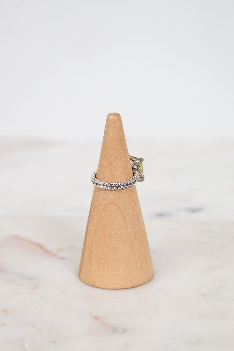 Silver ring on a wooden cone against a white background