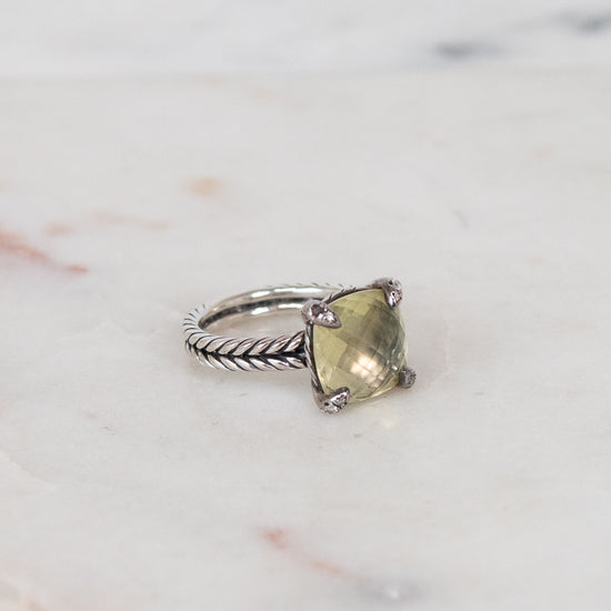 Silver ring with a green gemstone on a marble surface
