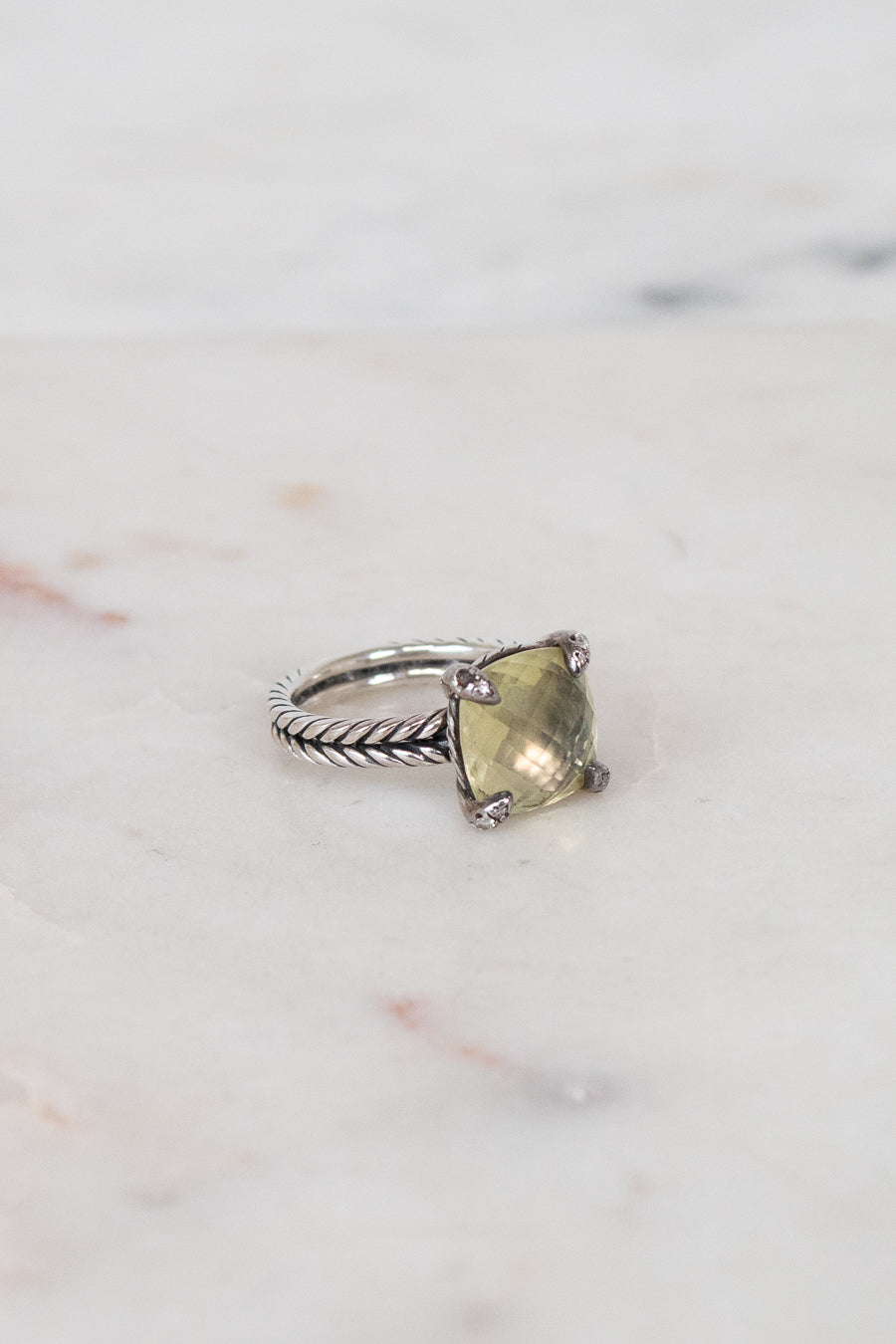 Silver ring with a green gemstone on a marble surface