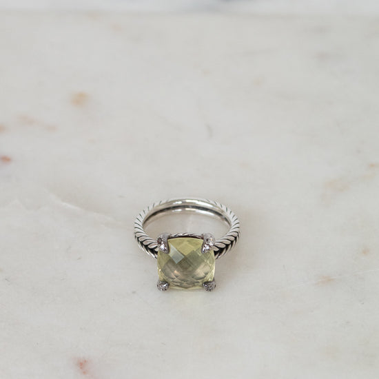 Silver ring with a green gemstone on a marble surface