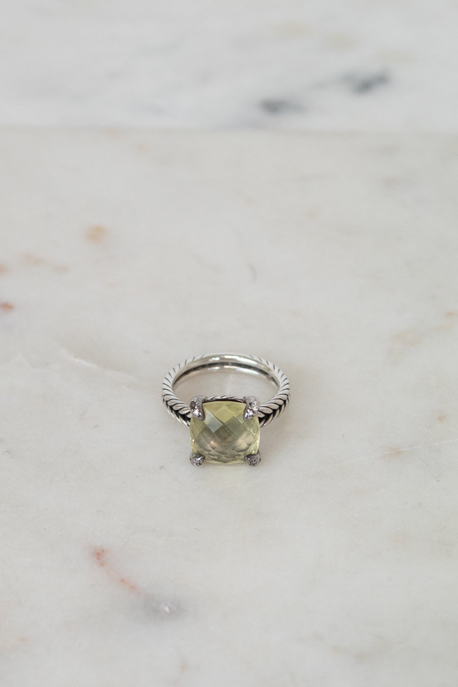 Silver ring with a green gemstone on a marble surface