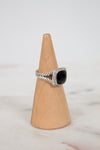 Silver ring with a black stone on a wooden cone against a light background