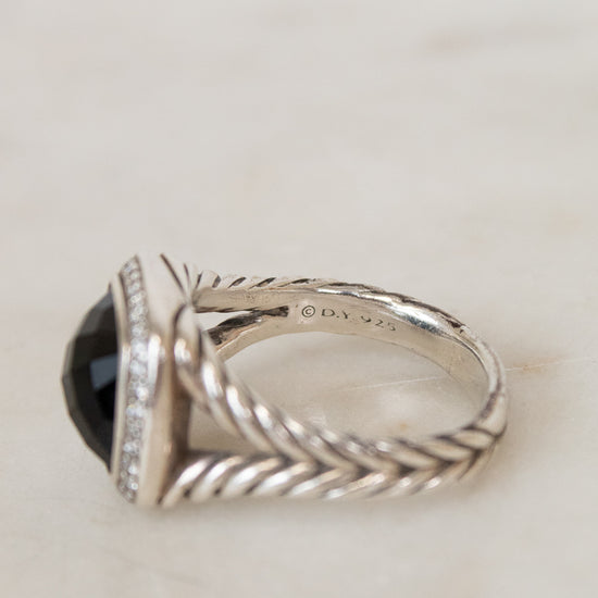 Silver ring with a black gemstone on a light background
