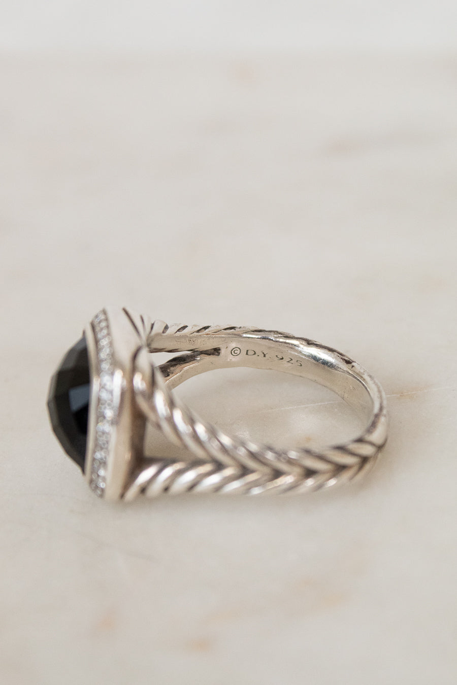Silver ring with a black gemstone on a light background