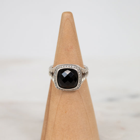 Ring with a black gemstone on a wooden cone against a light background