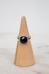 Ring with a black gemstone on a wooden cone against a light background