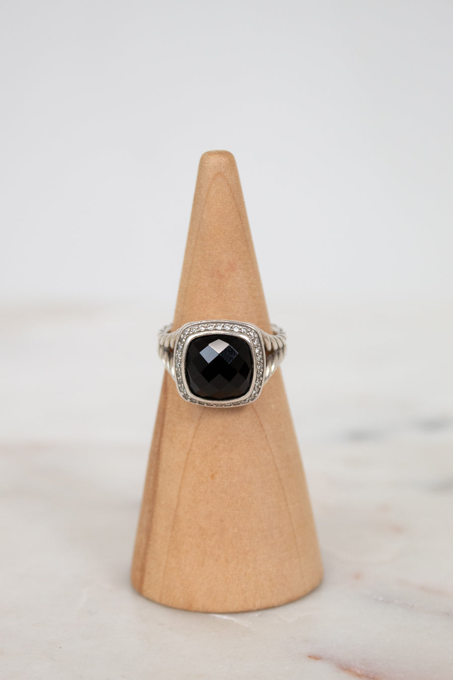 Ring with a black gemstone on a wooden cone against a light background