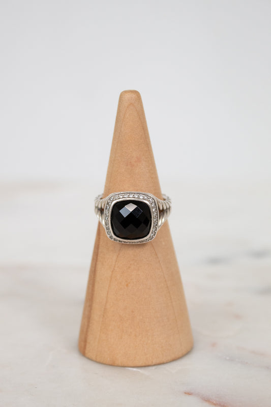 Ring with a black gemstone on a wooden cone against a light background