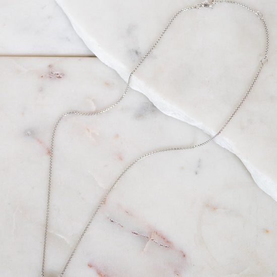 Necklace with a blue gemstone center detail on a marble surface