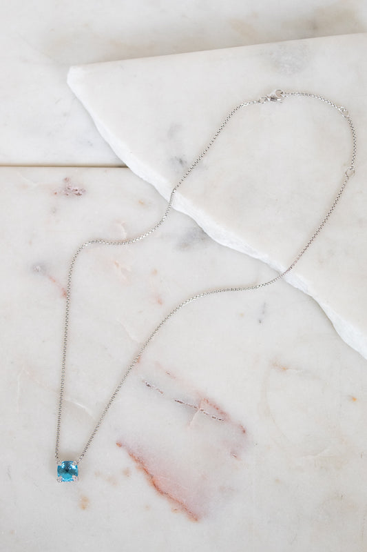 Necklace with a blue gemstone center detail on a marble surface