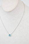Necklace with a blue center stone detail on a mannequin neck against a neutral background