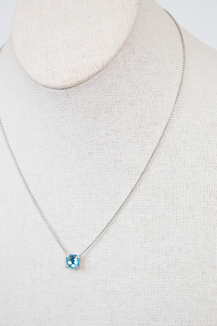 Necklace with a blue center stone detail on a mannequin neck against a neutral background