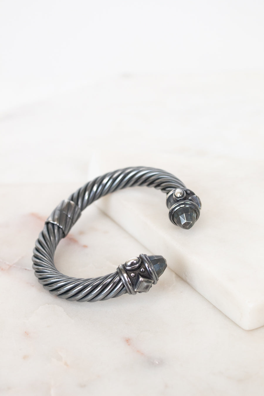 Silver bracelet with a detailed design on a white surface