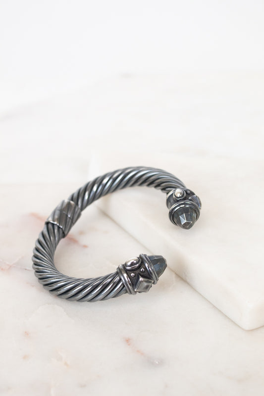 Silver bracelet with a detailed design on a white surface