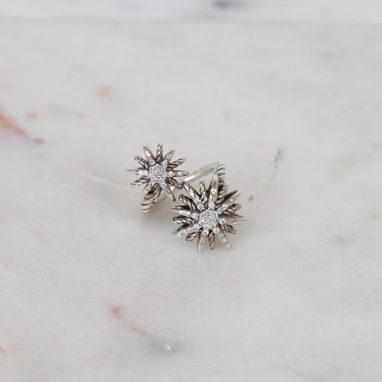 Silver ring with two starburst designs on a marble surface