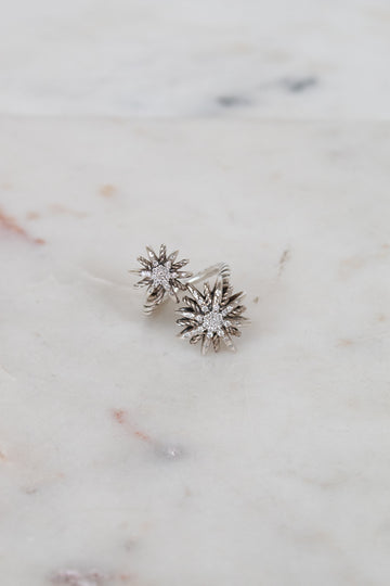 Silver ring with two starburst designs on a marble surface