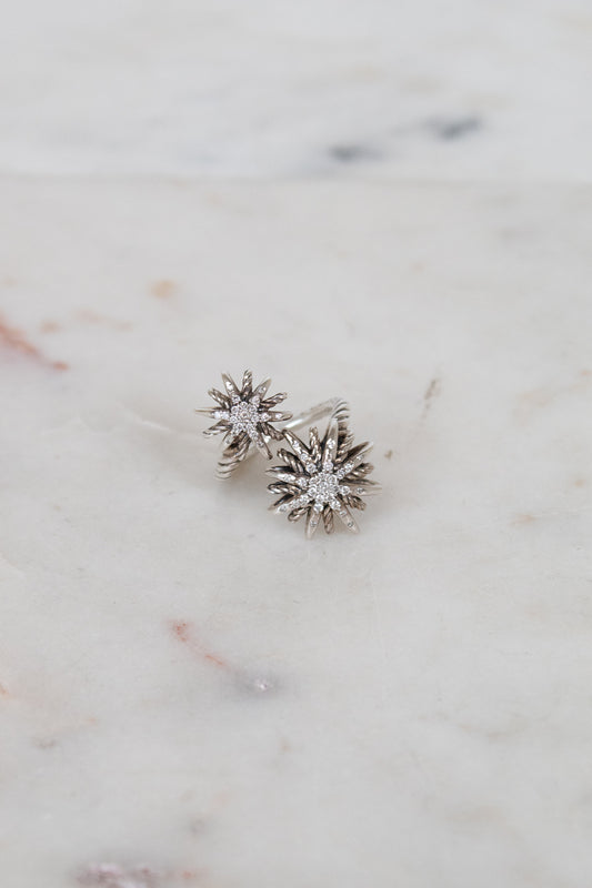 Silver ring with two starburst designs on a marble surface