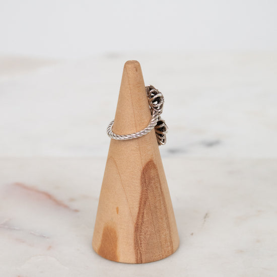 Silver ring on a wooden ring stand against a marble background