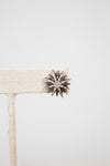 Silver star-shaped earring on a white background