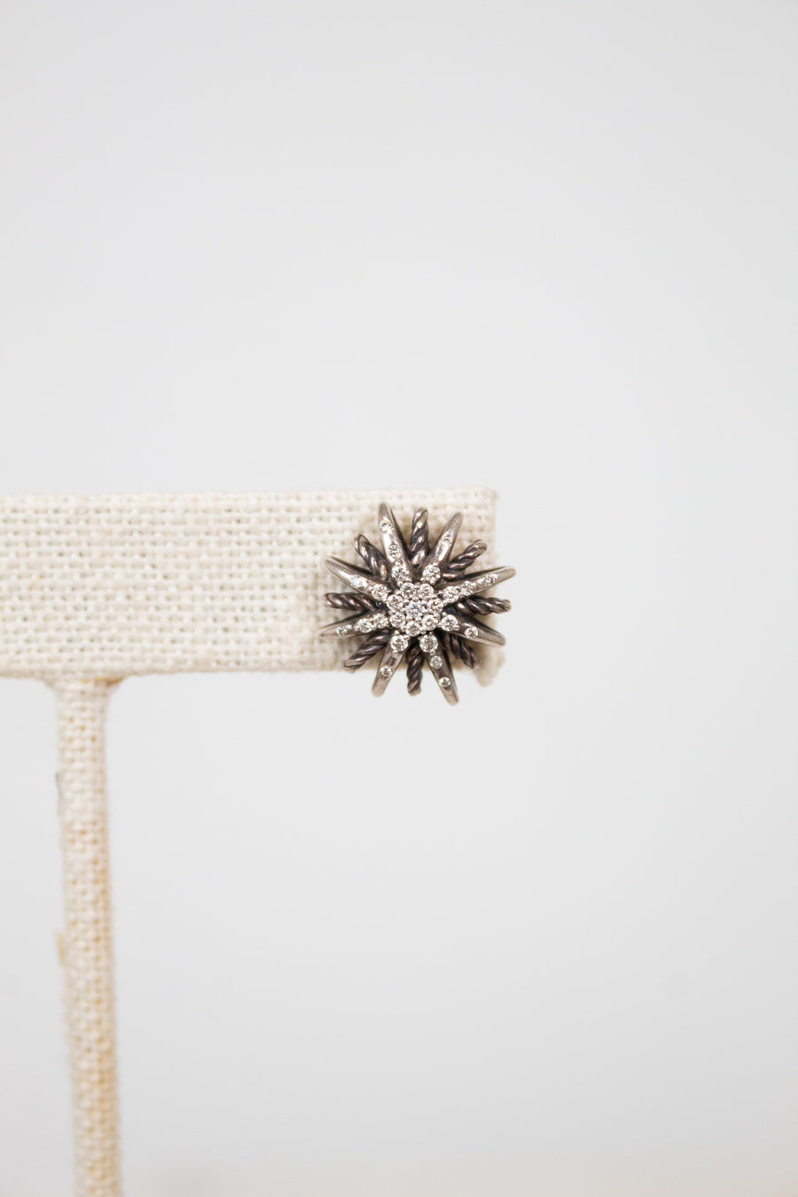 Silver star-shaped earring on a white background