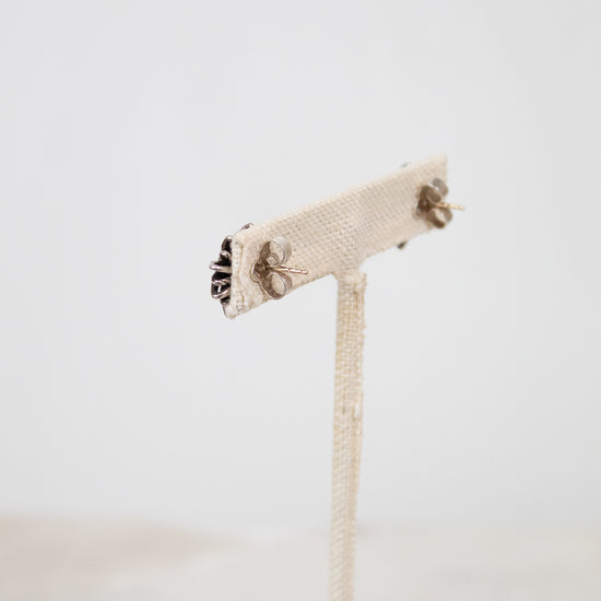 Silver stud earring backings on a white stand with a white background. 