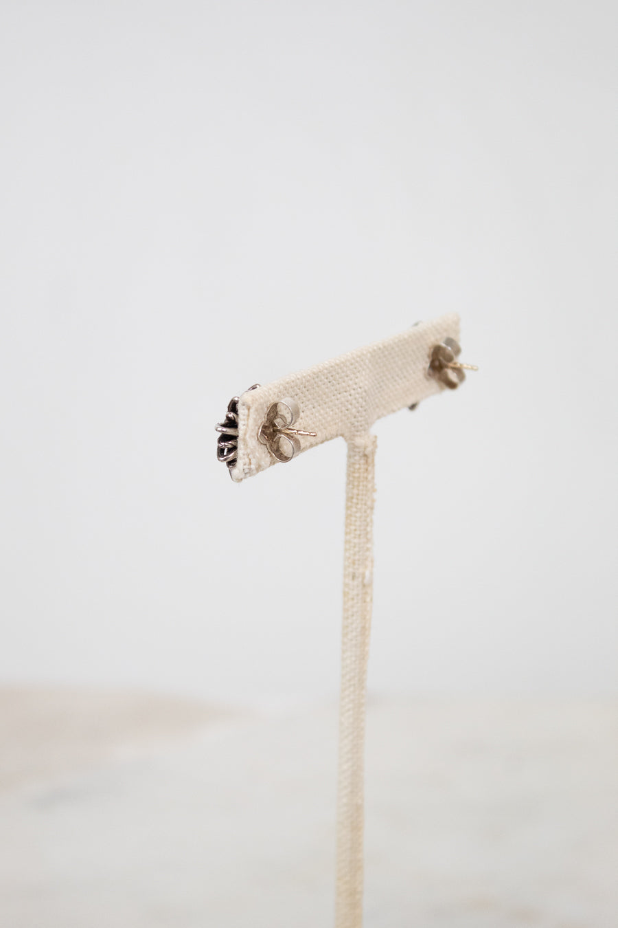 Silver stud earring backings on a white stand with a white background. 