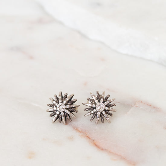 Silver starburst-shaped earrings on a marble surface