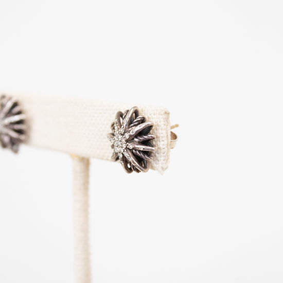 Silver earring with starburst design on a white background