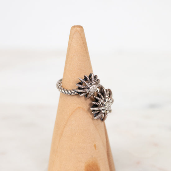 Silver starburst style ring on wooden cone with white background